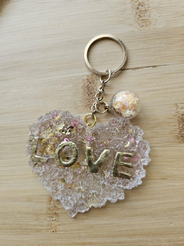 Porte clé coeur love détail rose transparent avec paillette rose et dorée et ecriture dorée en résine epoxy